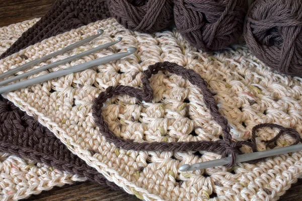 茶色とベージュのかぎ針編み布巾の上にかぎ針編みハート記号 — ストック写真