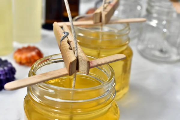 A close up image of pouring melted candle wax into glass molds for a small home-based candle making business.