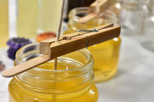 A close up image of pouring melted candle wax into glass molds for a small home-based candle making business.