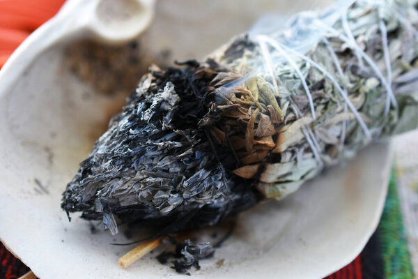 A close up image of a burning white sage smudge stick used for clearing energy and healing.