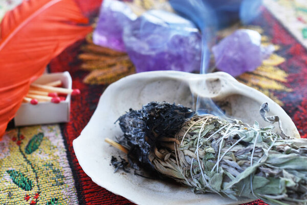 A close up image of a burning white sage smudge stick used for clearing energy and healing.