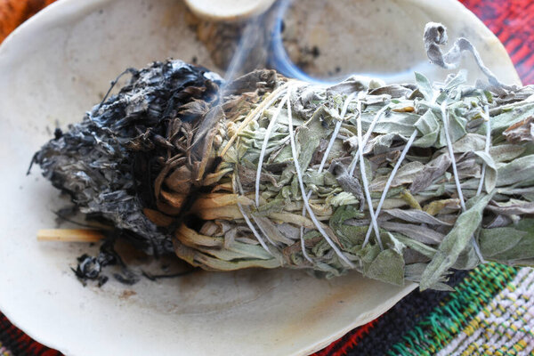 A close up image of a burning white sage smudge stick used for clearing energy and healing.