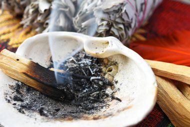 Yanan bir palo santo lekesinin yakın plan görüntüsü. Duman, kalp şeklini oluşturur..