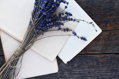 Kurumuş lavanta çiçeklerinin ve ahşap bir yazı masasında eski el yapımı kağıtların üst görüntüsü.. 