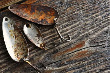 Eski ahşap bir masaya üç tane çok eski ve paslı olta kancası yakın çekim görüntüsü.. 