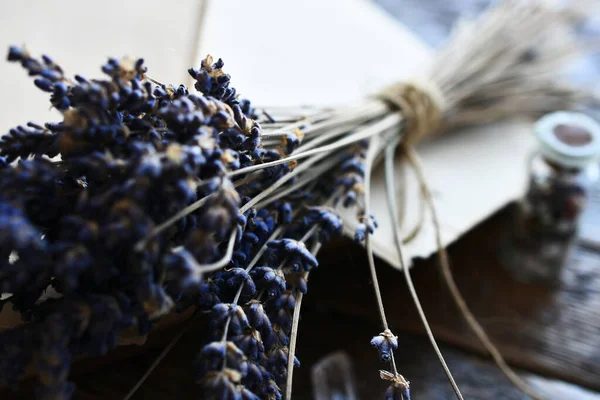 A close up image of old fashioned handmade writing paper with dried lavender flowers on a vintage writing desk.