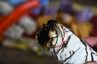 Enerji iyileştirme ve temizleme için kullanılan yanan beyaz adaçayı çubuğunu tutan bir kadın elinin yakın plan görüntüsü.. 