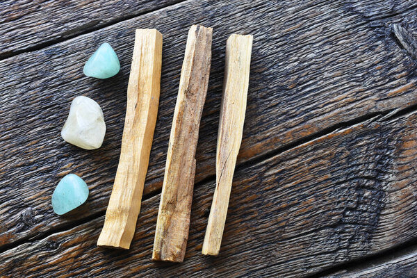 A close up image of three palo santo smudge sticks with green aventurine and citrine healing crystals. 