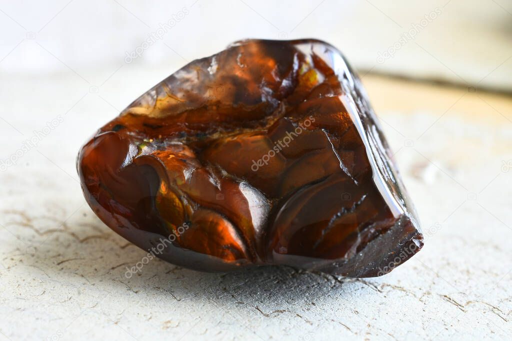 A close up image of a beautiful fire agate crystal on a white wooden background. 