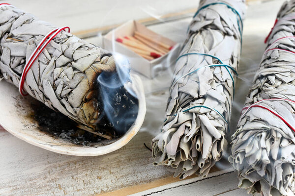 A close up image of a burning white sage smudge stick used for energy clearing and healing. 