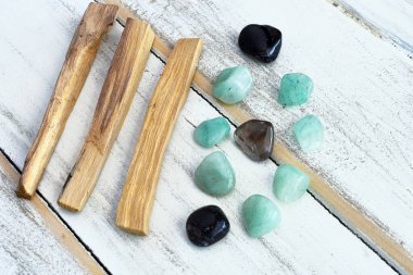 Palo Santo leke çubukları ve beyaz ahşap bir masa üzerindeki iyileştirici kristallerin yakın plan görüntüsü.. 