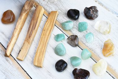 Palo Santo leke çubukları ve beyaz ahşap bir masa üzerindeki iyileştirici kristallerin yakın plan görüntüsü.. 