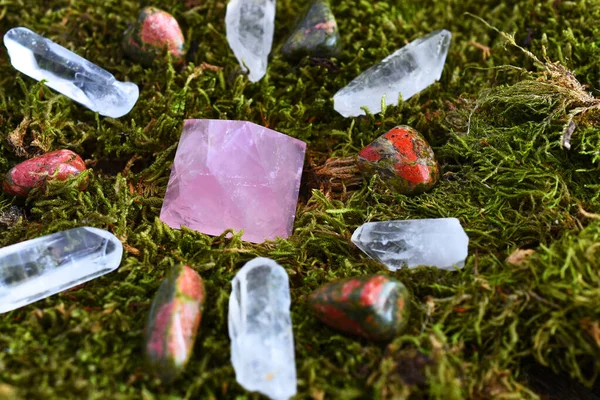 A close up image of a crystal healing grid on lush green moss.