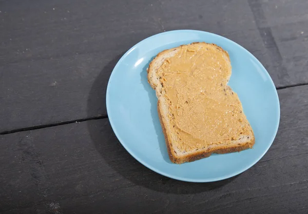 Pan con mantequilla de maní sobre fondo de madera — Foto de Stock