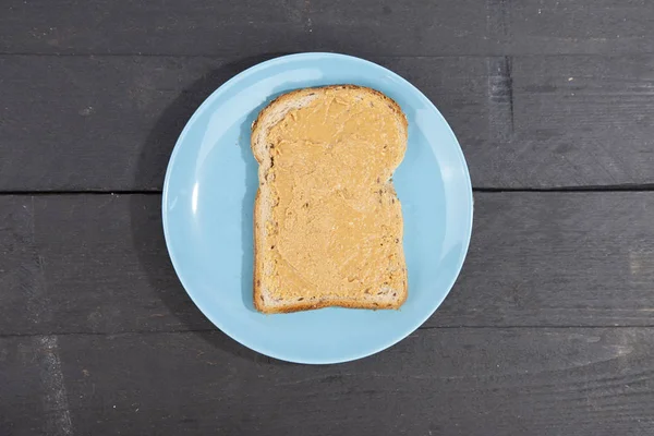 Pan con mantequilla de maní sobre fondo de madera — Foto de Stock