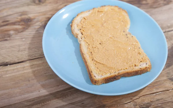 Pão com manteiga de amendoim sobre fundo de madeira — Fotografia de Stock