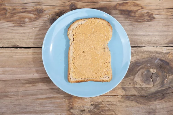 Pan con mantequilla de maní sobre fondo de madera — Foto de Stock