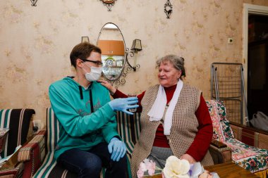 MINSK, BELARUS - 25 Şubat 2020: Sosyal hizmetler gönüllüsü yaşlı kadına Coronavirus 'a yardım etti