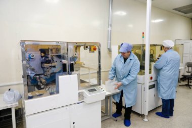 MINSK, BELARUS - 25 Şubat 2020: Electronics Factory Worker a Printed Circuit Board through a Digital Microscope High Tech Facity