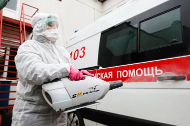 MINSK, BELARUS - 1 Mart 2020: Coronavirus 'tan ambulansı dezenfekte eden kadın