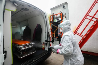 MINSK, BELARUS - 1 Mart 2020: Coronavirus 'tan ambulansı dezenfekte eden kadın