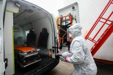 MINSK, BELARUS - 1 MARCH, 2020: woman disinfects ambulance from coronavirus clipart
