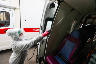 MINSK, BELARUS - 1 Mart 2020: Coronavirus 'tan ambulansı dezenfekte eden kadın