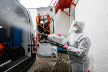 MINSK, BELARUS - 1 Mart 2020: Coronavirus 'tan ambulansı dezenfekte eden kadın