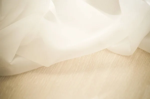 Beige tulle shines on the wooden table — Stock Photo, Image