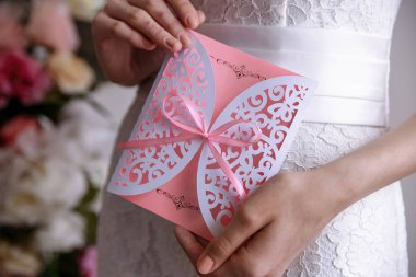 Düğün davetiyesi pembe kart gelinin elinde