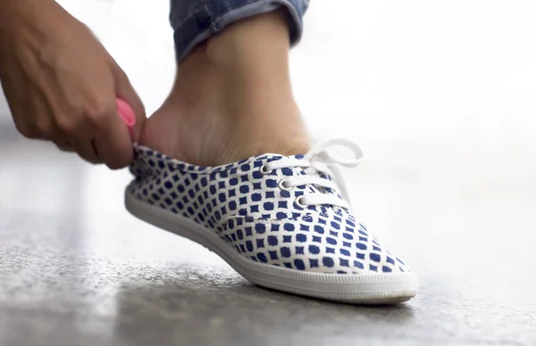 Дівчина зв'язує шнурки на кросівки — стокове фото