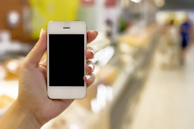 Süpermarket arka planında cep telefonu tutan kadın, iş konsepti