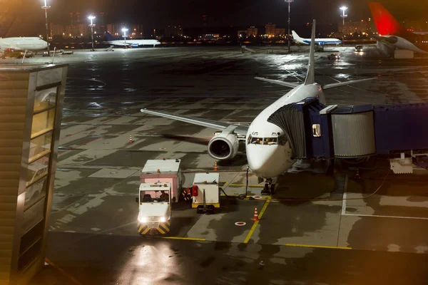 aircraft parked at the airport and preparation for next flight. Loading cargo on the plane in airport terminal at night. Workers cargo airplane service.