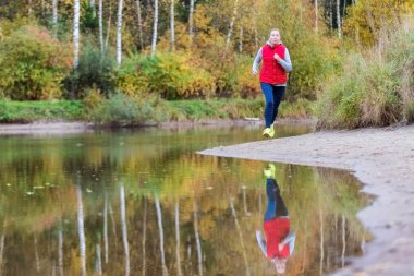 Bir kız ormanda gölün kıyısında çalışır.