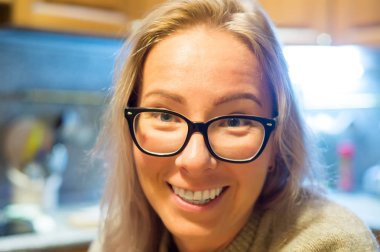 Bir kadın mutfakta oturuyor ve gülümseyerek. Bir ev kadını