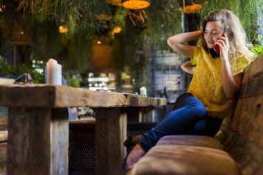 Genç, çekici bir kadın cep telefonuyla arıyor. Boş zamanlarında kafede tek başına oturuyor. Güzel gülüşlü çekici bir kadın kafede dinlenirken cep telefonuyla konuşuyor.