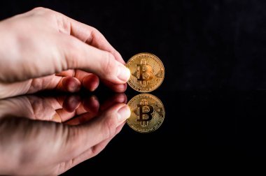 elinde siyah bir zemin üzerine bitcoin. Yazı tura ayna yansıması