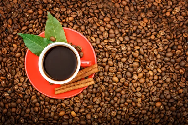 A red coffee cup stands on the grains of fried coffee. — Stock Photo, Image