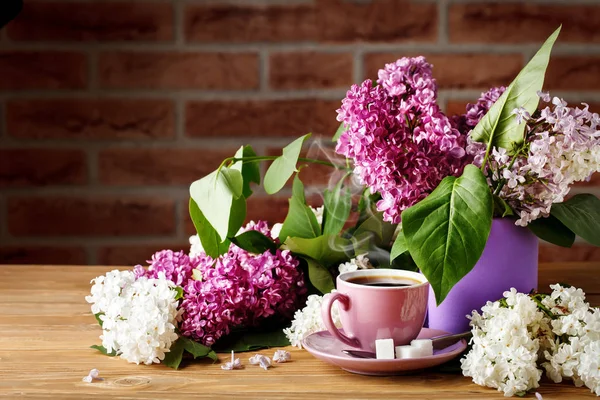 Bodegón con ramas de lila y una taza de café sobre una mesa de madera . —  Fotos de Stock