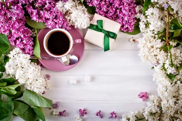 Bodegón con ramas de lila y una taza de café sobre una mesa de madera . — Foto de Stock