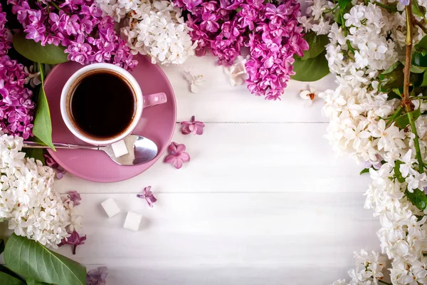 Bodegón con ramas de lila y una taza de café sobre una mesa de madera . —  Fotos de Stock