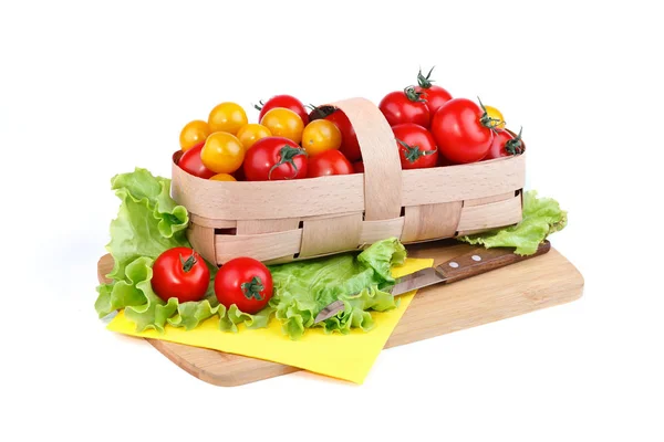 Tomates amarillos y rojos se encuentran en la cesta sobre un fondo blanco . — Foto de Stock