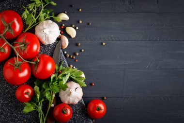 Natürmort domates, sarımsak, maydanoz ve karabiber siyah ahşap kurullarında.