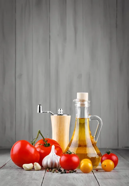 Zátiší z rajčat, česneku a olivového oleje na šedá prkna. — Stock fotografie