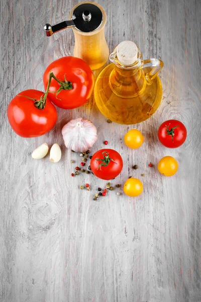 Zátiší z rajčat, česneku a olivového oleje na šedá prkna. — Stock fotografie