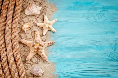 Deniz yıldızı, çakıl ve kabukları bir mavi ahşap arka plan üzerinde yalan. Etiketler için bir yer var..