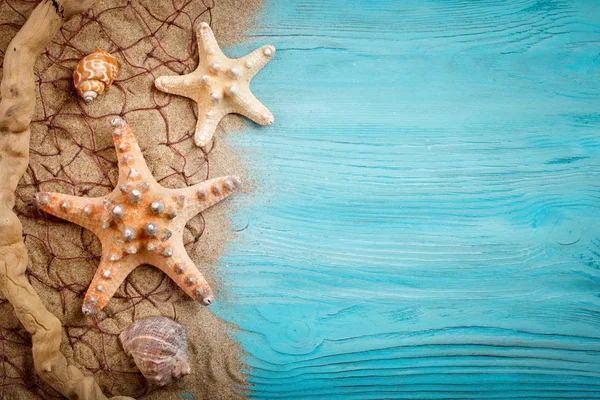 Estrella de mar, guijarros y conchas sobre un fondo azul de madera. Hay un lugar para las etiquetas . — Foto de Stock