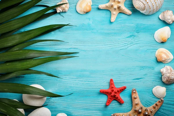Moře hvězd, moře kameny, palm listy a vložek, leží na modrém pozadí dřevěná. Zde je místo pro štítky. — Stock fotografie