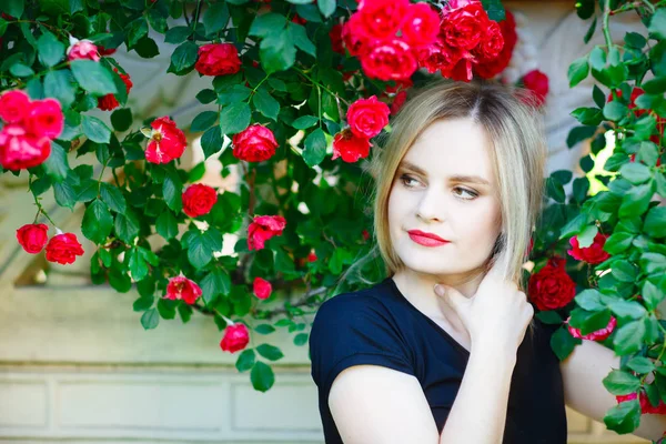 Vacker ung kvinna i en trädgård med rosor. — Stockfoto