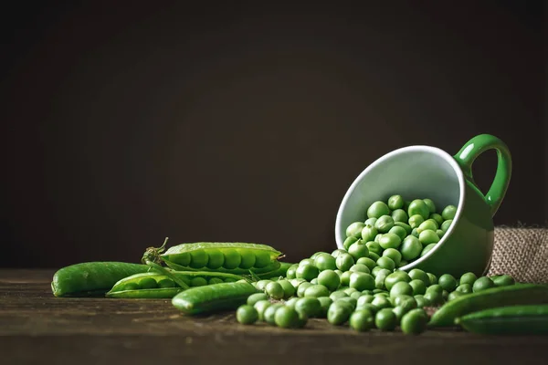 Délicieux pois verts mûrs couchés sur une table en bois. — Photo